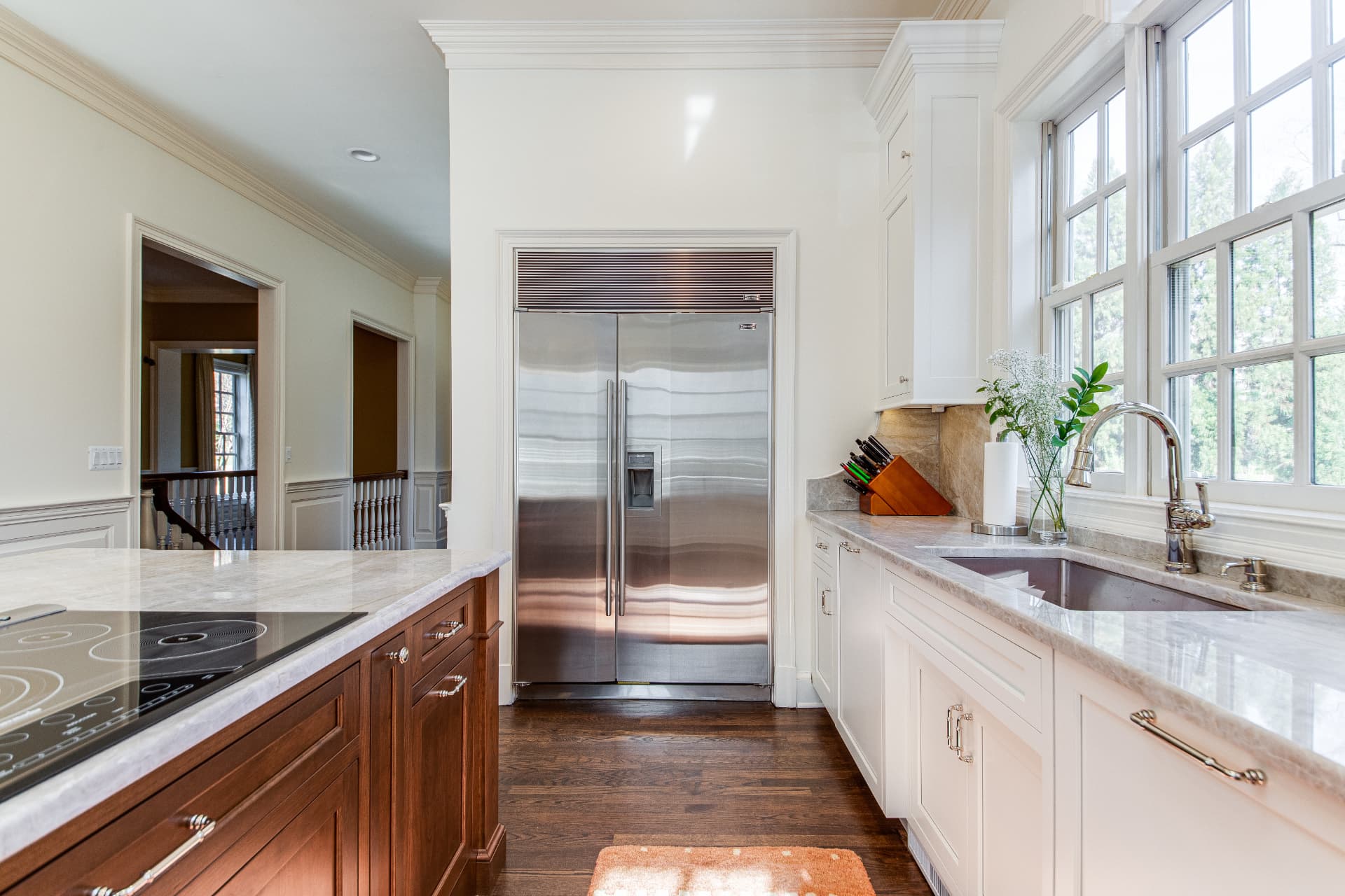 Bright kitchen with white cabinetry, marble countertops, and a wood island